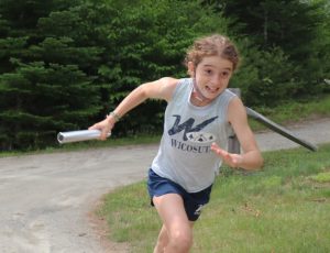 A girl holds a baton and runs.